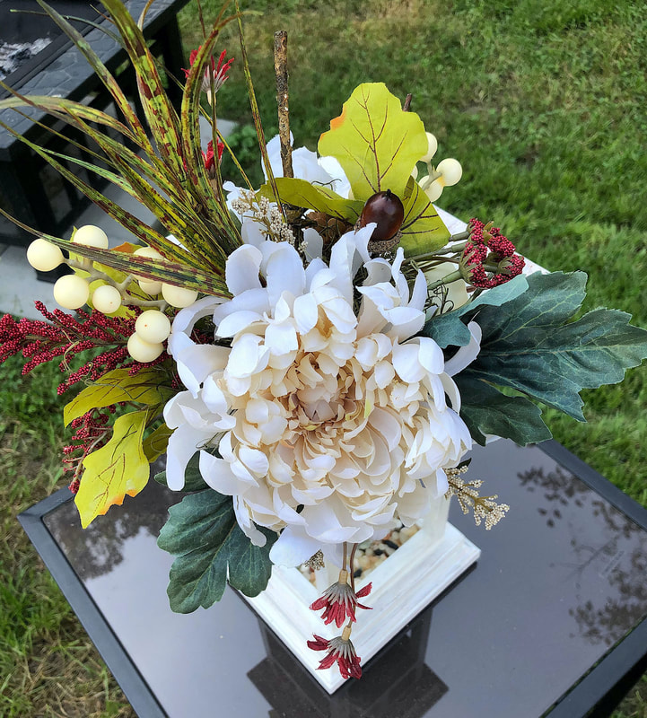 Fall faux floral arrangement on top of handcrafted wood lantern.