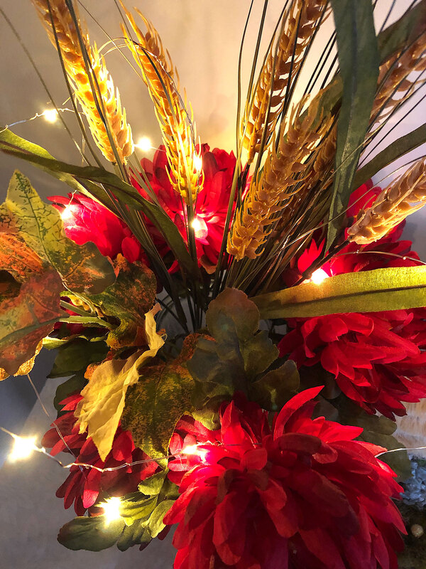 Fall themed faux floral arrangement lit with fairy lights.