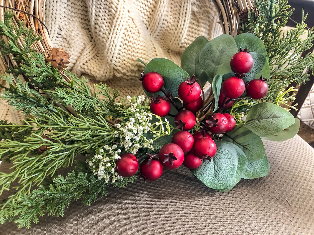 Closeup of faux berries and greenery on a DIY wreath.