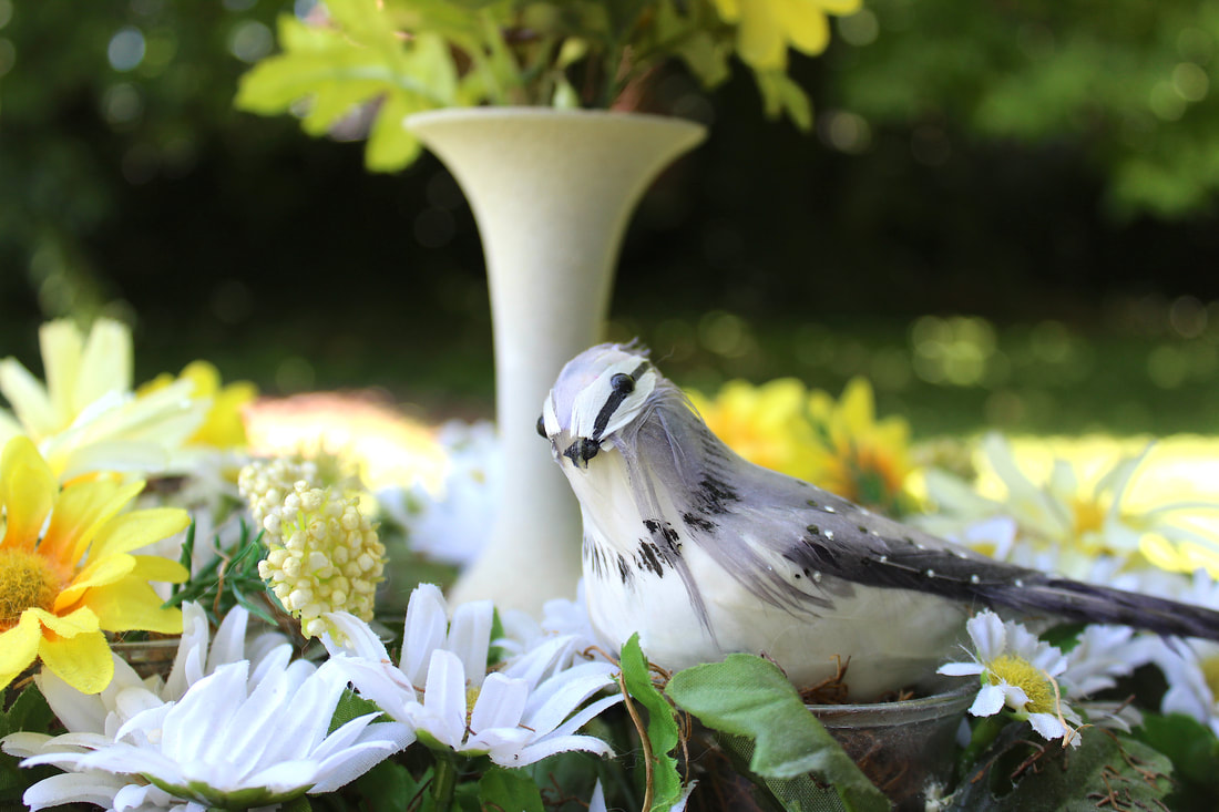 Faux bird with yellow and white faux florals.