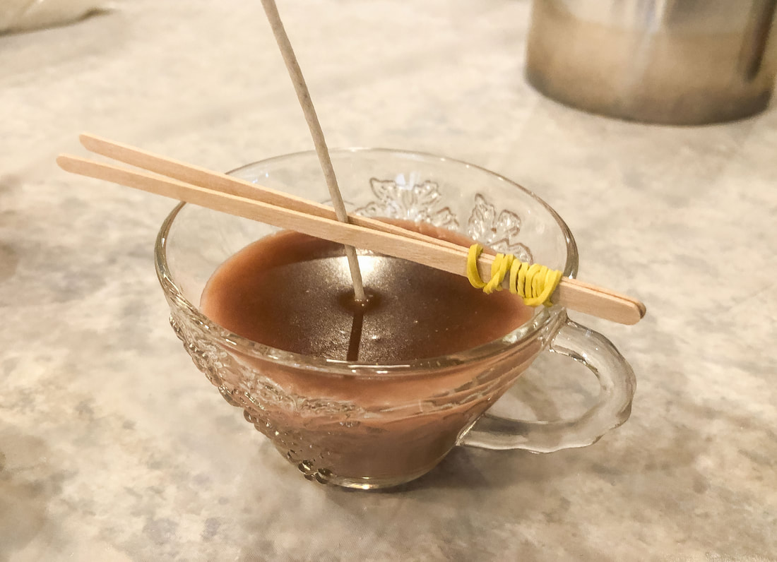 Homemade candle with wax setting in glass tea cup.