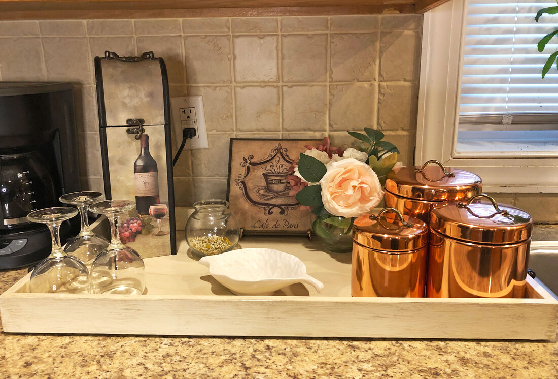 Coffee and wine station with thrifted wine box, cafe plaque, and copper tins.