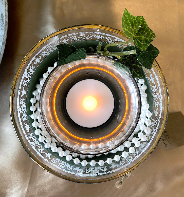 Top down photo of repurposed glassware with faux vines and pearls.